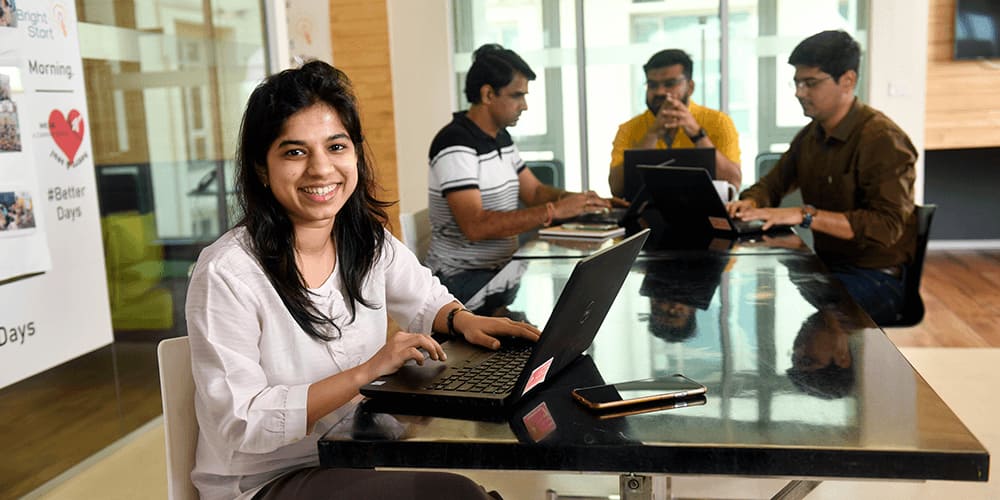 Portrait of smiling girl working with her laptop on table in Kellogg's office
