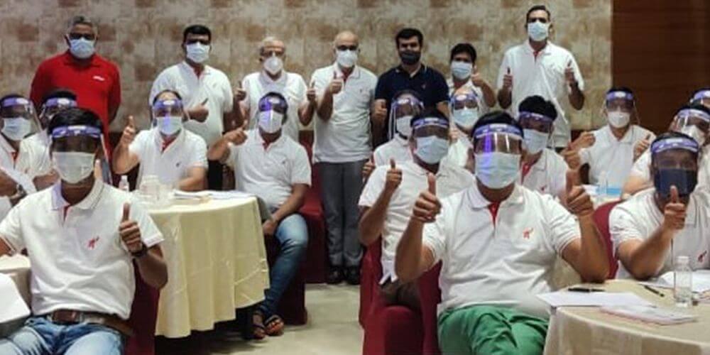 Employees showing thumbs up by wearing a mask and face shield during a gathering