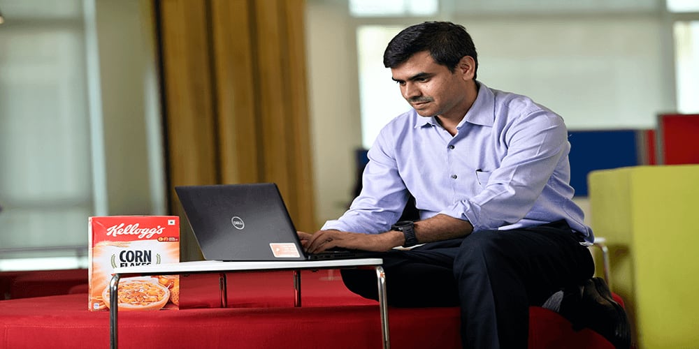Man working on laptop with box of Kellogg's Corn Flakes beside him