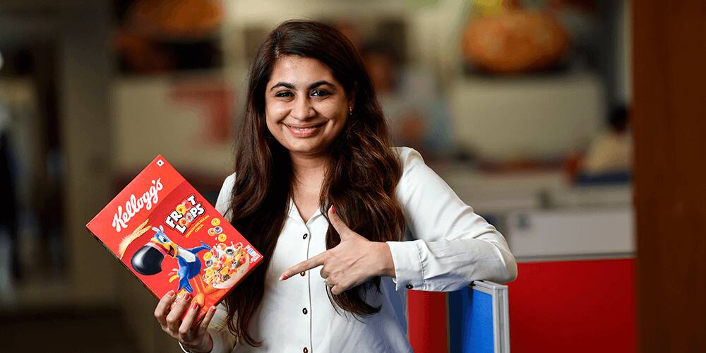 Smiling girl pointing finger to box of Kellogg's Froot Loops on other hand