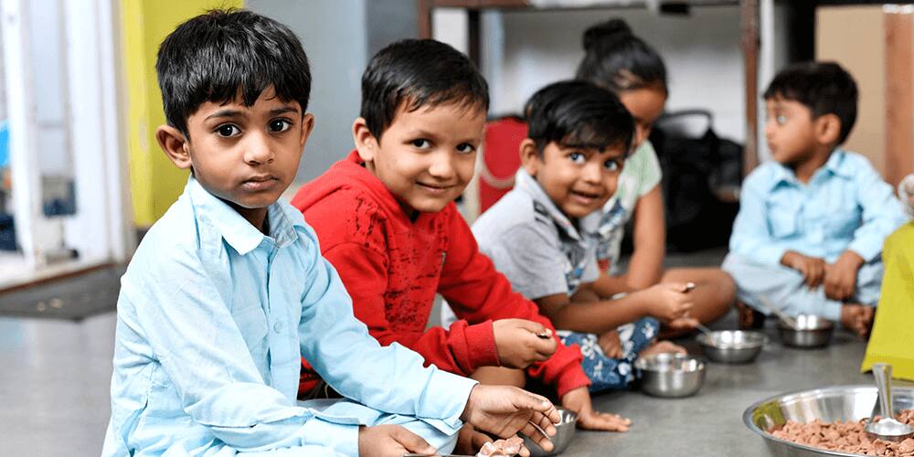 Children having breakfast sitting on floor with Kellogg's cereal bowl