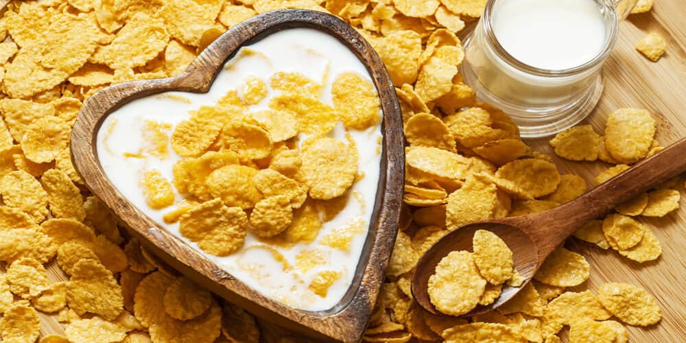 Corn flakes with milk in a heart-shaped wooden bowl