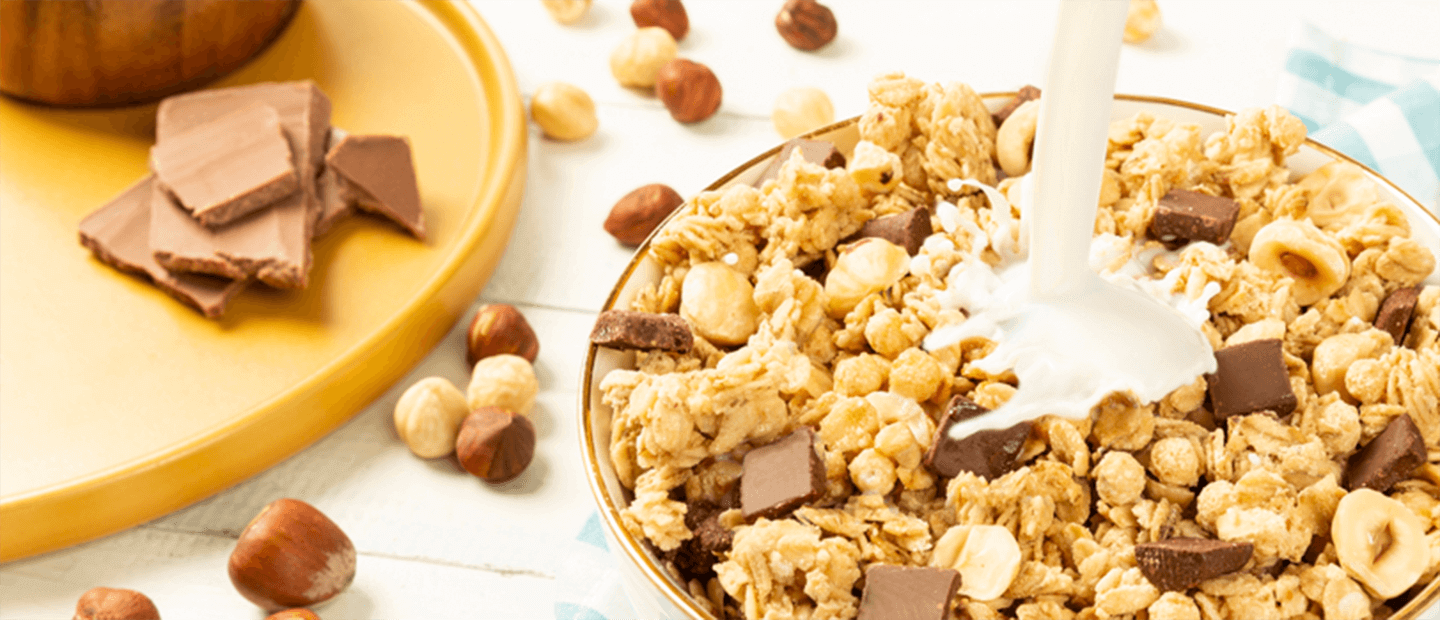 Pouring milk in a  bowl of Granola clusters with chocolate and hazelnut