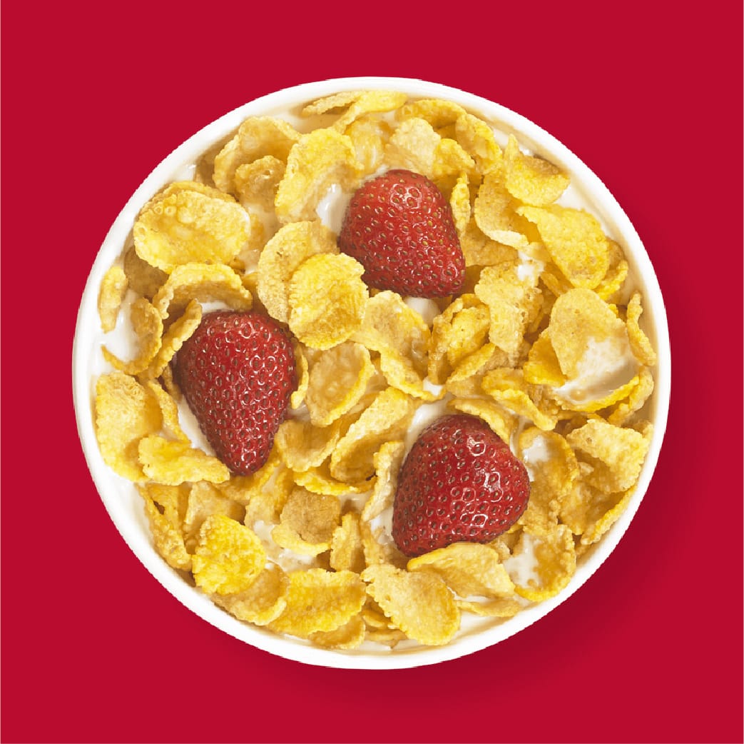 A Bowl Of Kellogg's Corn Flakes With Milk and Strawberry with red background